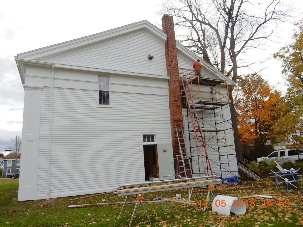 Mike is scraping and painting the gable. Metal trim is being applied to the cornice.