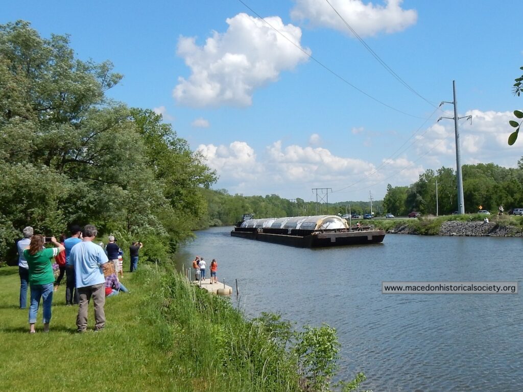 A group of spectators watch the first barges heading west.